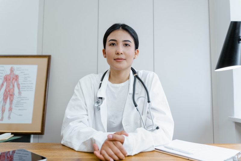 Female breast care specialist wearing white coat and sitting at desk.