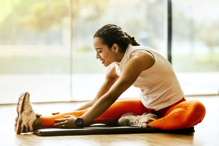 Healthy woman stretching on gym mat.